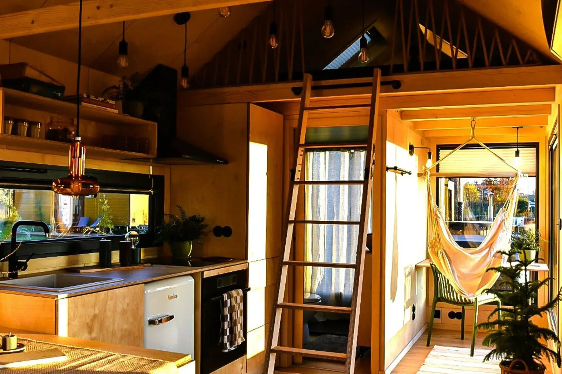 Inne i et minihus: kjøkkenet, en stige opp til sovehemsen og en hengekøye ved vinduet